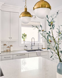 timeless bright white kitchen with marble counters striped roman shade and gold pendant lights